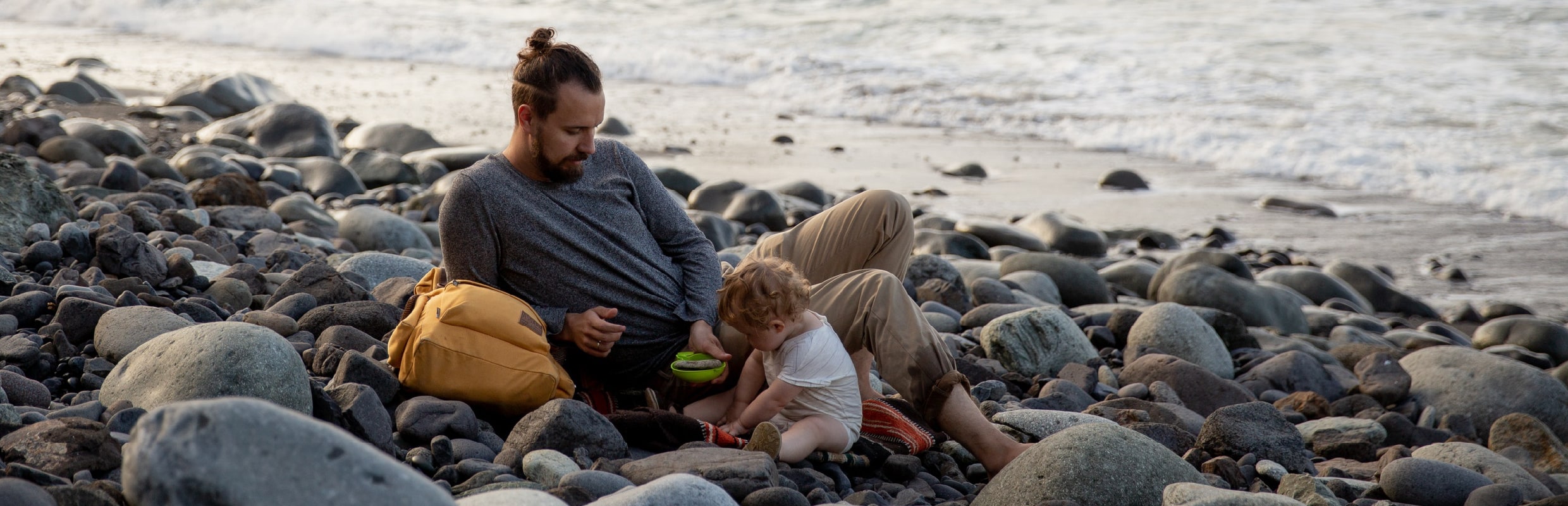 Dad and child on stony beach playing