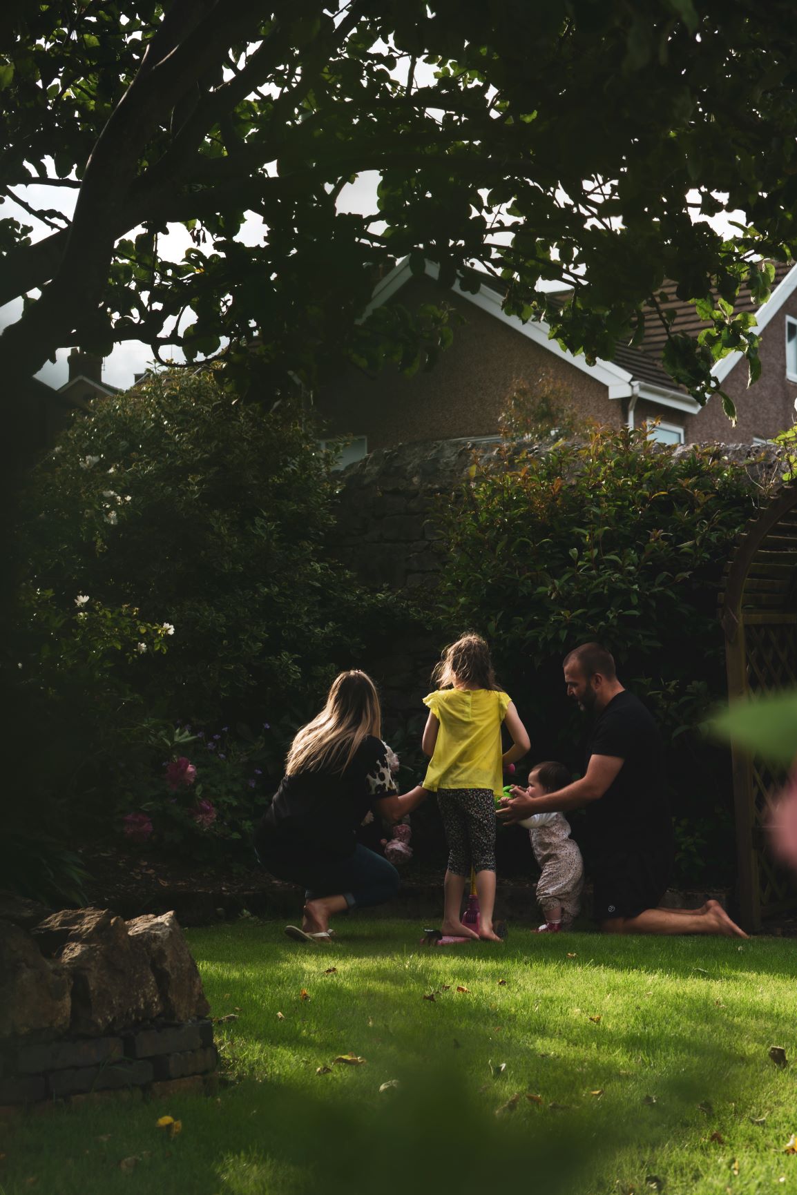 Family of four in garden watering flowers