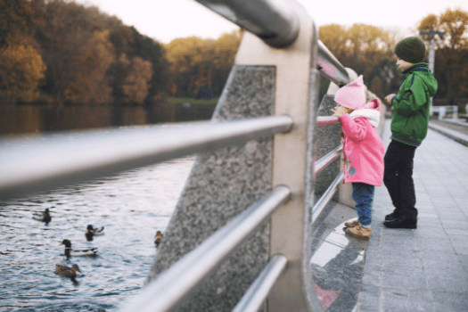 Brother (approx 6) and sister (approx 3) looking over a bridge in winter