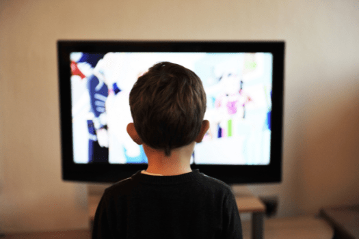 Little boy with brown hair watching cartoons on TV