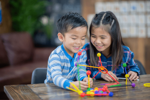 Brother and sister building with circles and straws