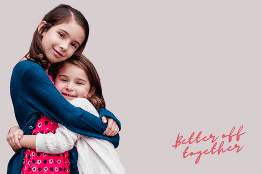 Little girl aged around 8 hugging her little sister around 4 years old